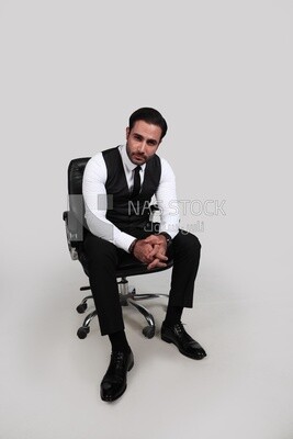 Photo of a businessman with a formal suit sitting on a chair and looking at the camera, business development and partnerships, business meeting, Model