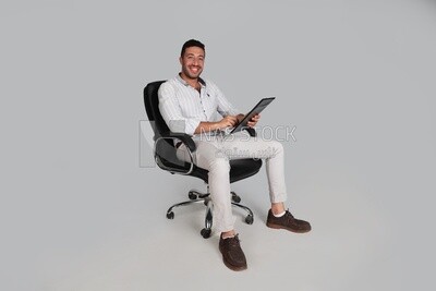 Photo Of a Handsome man sitting on a chair holding decomunts, Smiling Man, Wearing Casual Clothes Posing In a Light Room Interior, Smiling At the Camera, looking away