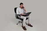 Photo of a handsome man with casual wear sitting on a chair working on a laptop while talking on the phone, business development and partnerships, business meeting, Model