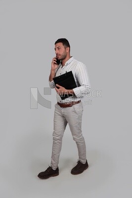 Photo Of a Handsome man standing and talking on his phone, Smiling Man, Wearing Casual Clothes Posing In a Light Room Interior, Smiling At the Camera, looking away