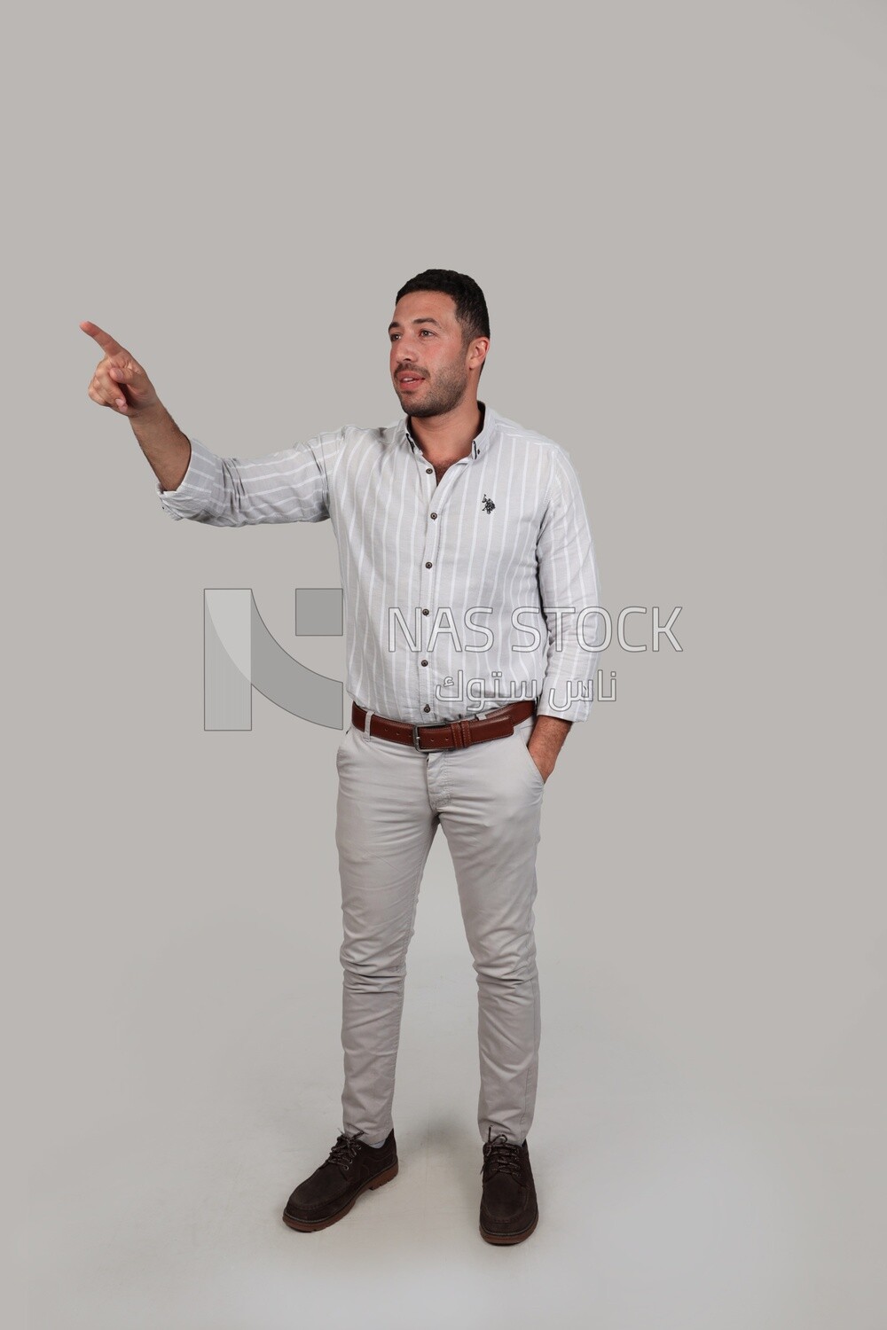 Photo Of a Handsome man standing and pointing away, Smiling Man, Wearing Casual Clothes Posing In a Light Room Interior, Smiling At the Camera, looking away