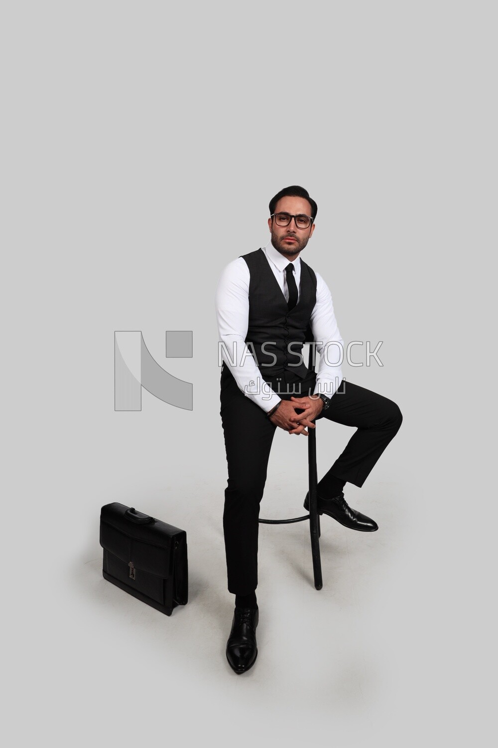 Photo of a businessman with a formal suit sitting on a chair and looking at the camera, business development and partnerships, business meeting, Model