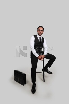 Photo of a businessman with a formal suit sitting on a chair and looking at the camera, business development and partnerships, business meeting, Model