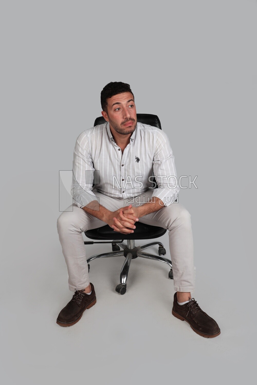 Photo Of a Handsome man sitting on a chair, Smiling Man, Wearing Casual Clothes Posing In a Light Room Interior, Smiling At the Camera, looking away