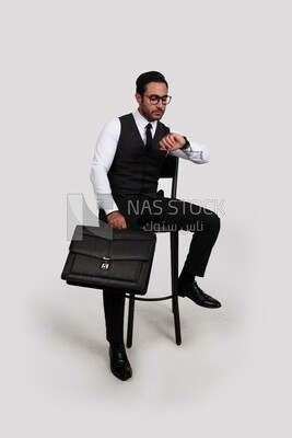 صورة لرجل وسيم يرتدي نظارات ويمسك حقيبة جلدية وينظر إلى الساعة ، وتطوير الأعمال والشراكة ، واجتماع العمل ، موديل