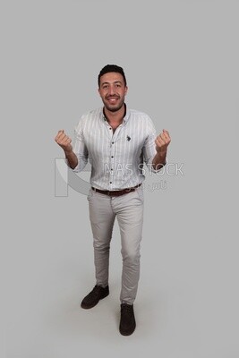 Photo Of a Handsome man standing with hand gestures, Smiling Man, Wearing Casual Clothes Posing In a Light Room Interior, Smiling At the Camera, looking away