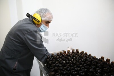 Worker placing bottles to fill medicine