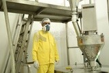 Factory worker wearing a mask and a yellow work suit