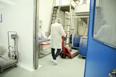 Specialist who works in a pharmaceutical factory and wears a white coat and a hair cap
