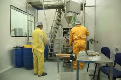 Workers in work uniforms in a factory watching the movement of the machine and its steps