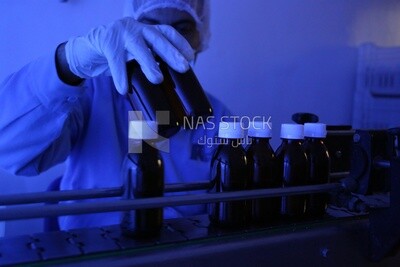 Chemist at a pharmaceutical factory selects two bottles of medicine to test their safety