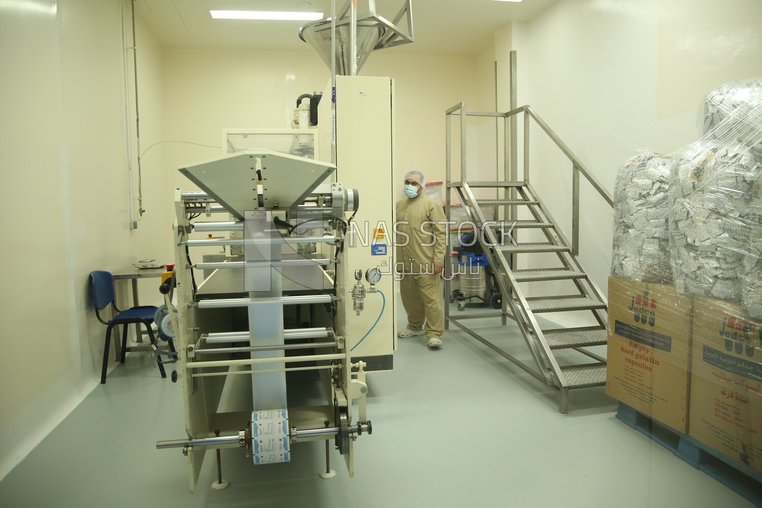 Factory worker standing next to a machine and wearing a work uniform