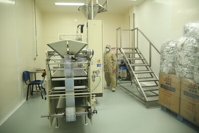 Factory worker standing next to a machine and wearing a work uniform