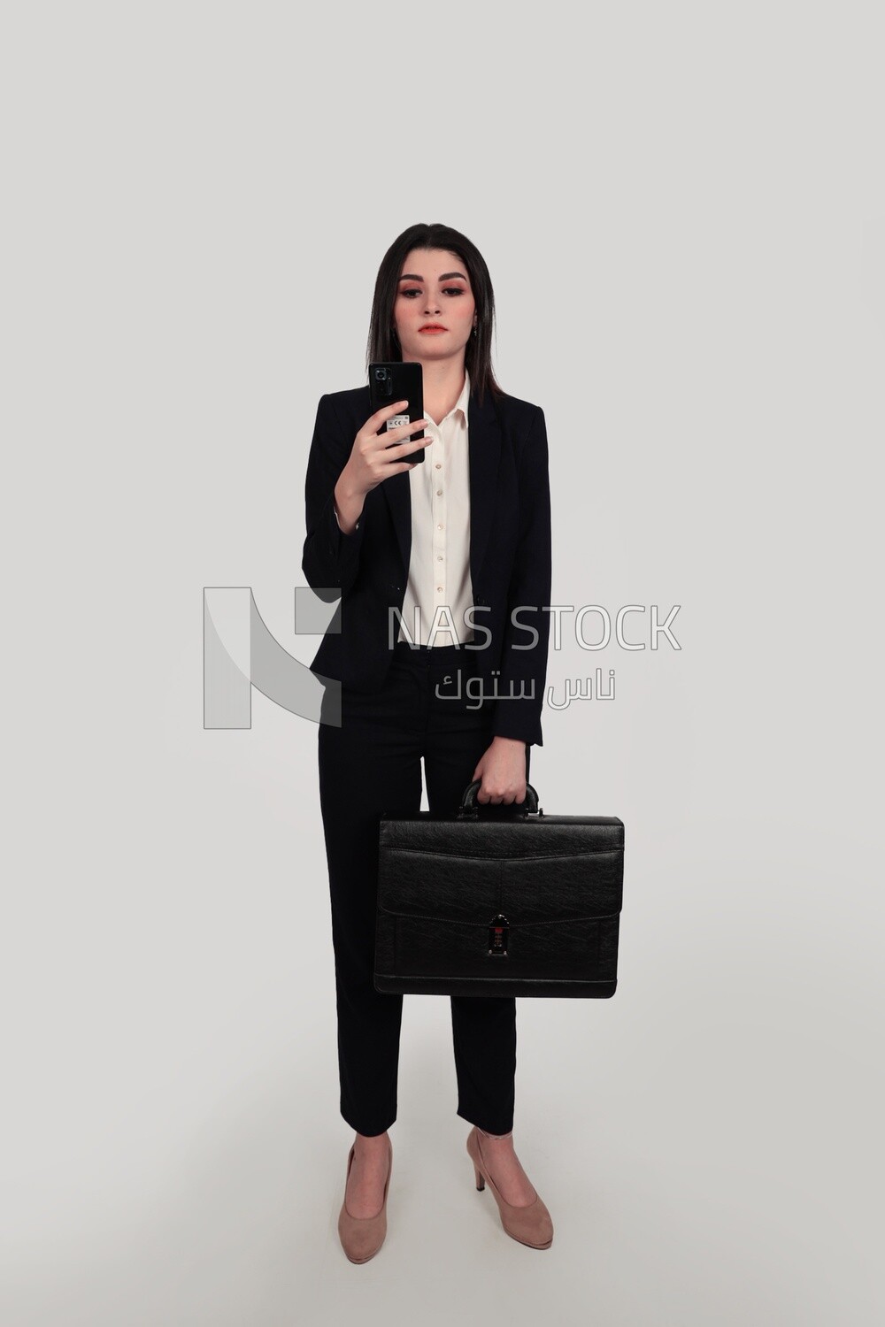 Photo of a businesswoman with formal wear standing and holding a leather bag checking her mobile, business development and partnerships, business meeting, Model