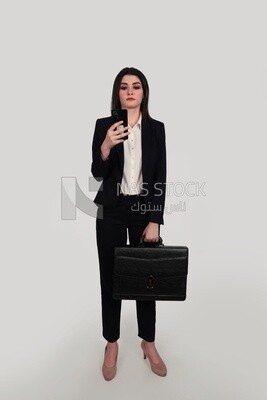 Photo of a businesswoman with formal wear standing and holding a leather bag checking her mobile, business development and partnerships, business meeting, Model