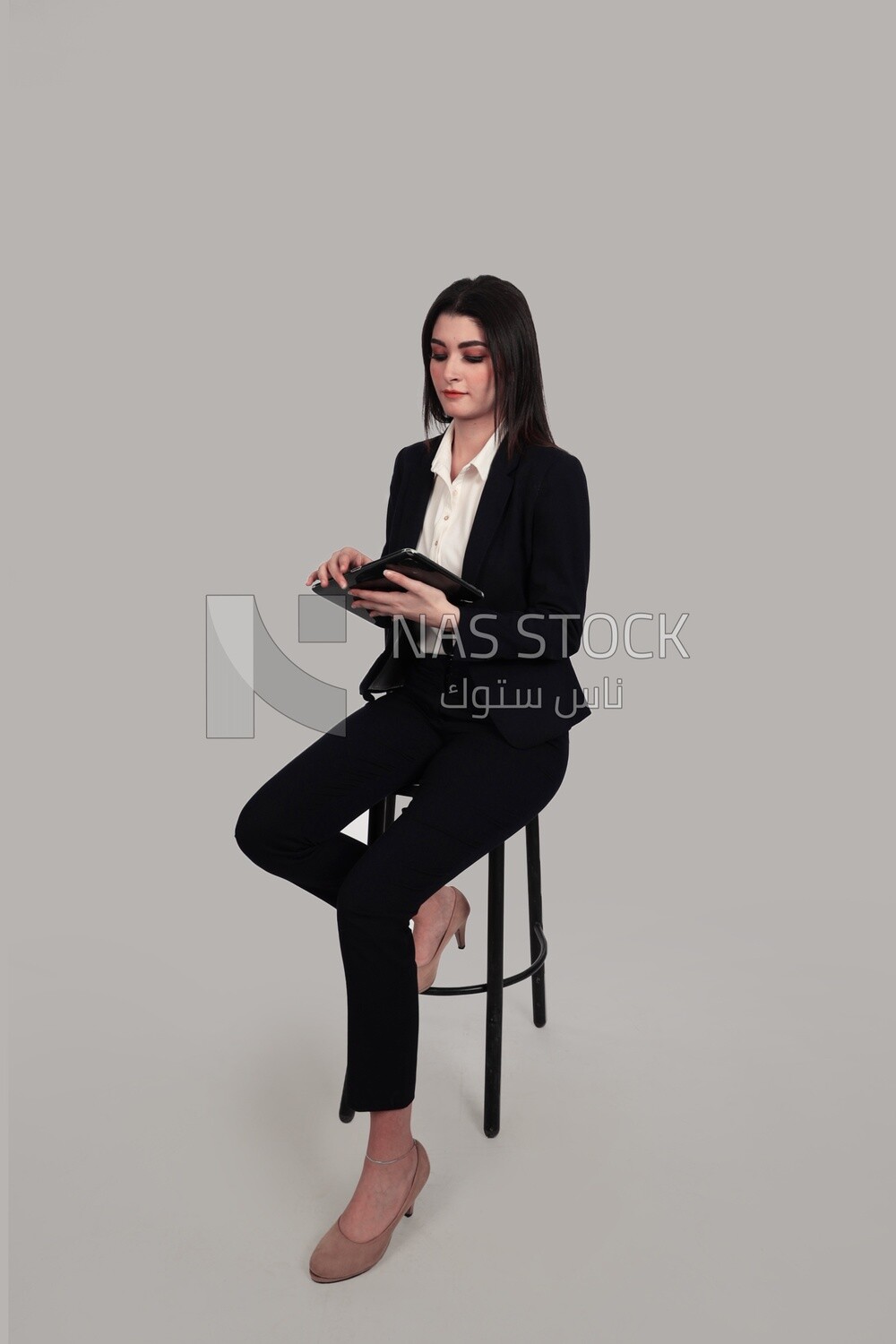 Photo of a businesswoman with a formal suit sitting on a chair and holding a tablet, business development and partnerships, business meeting, Model