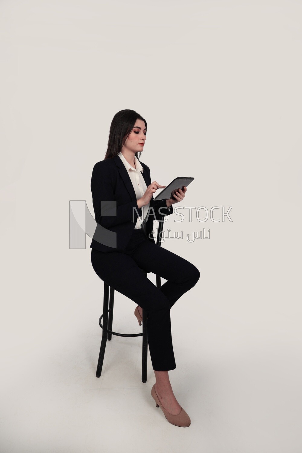 Photo of a businesswoman with a formal suit sitting on a chair and holding a tablet, business development and partnerships, business meeting, Model