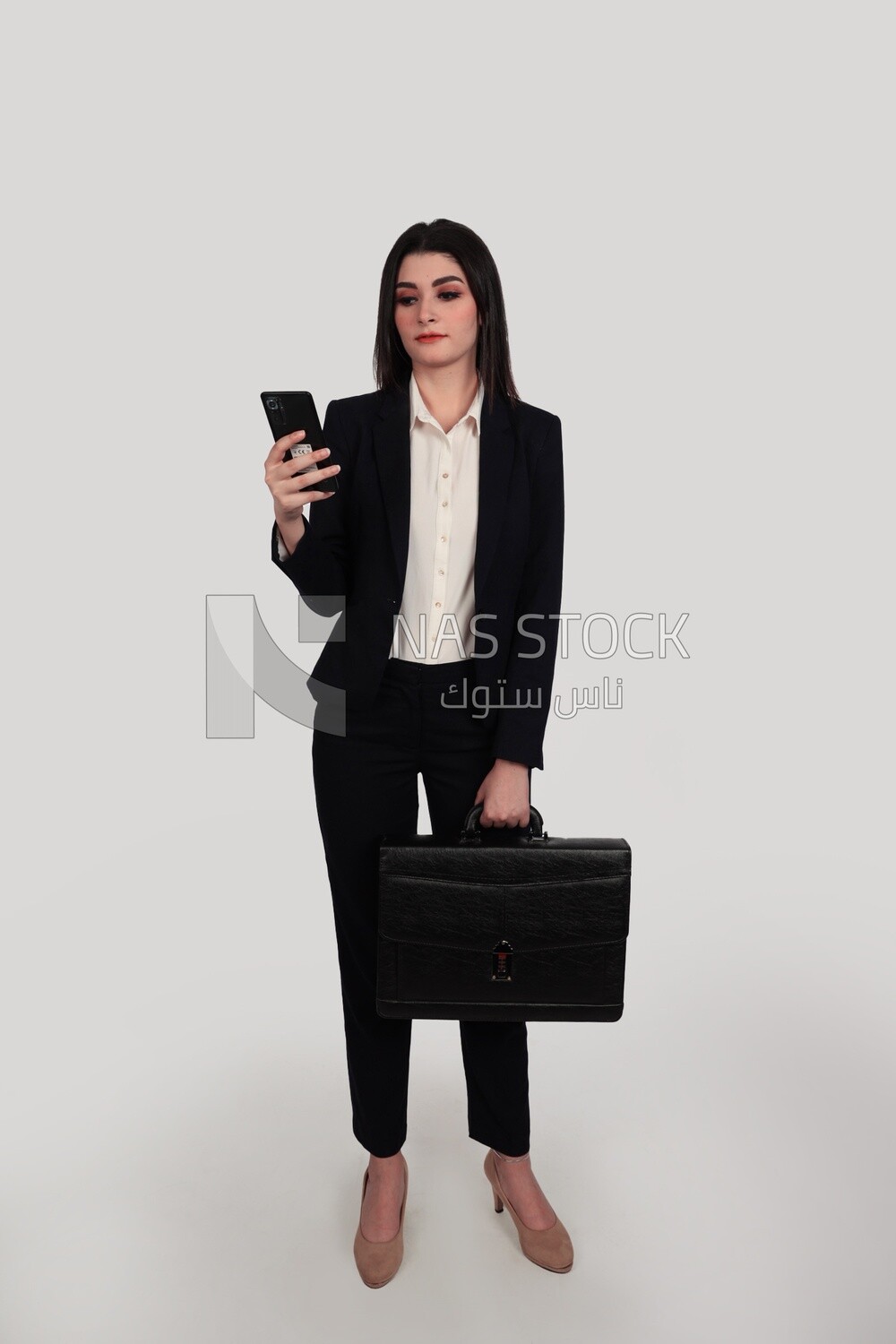 Photo of a businesswoman with formal wear standing and holding a leather bag checking her mobile, business development and partnerships, business meeting, Model