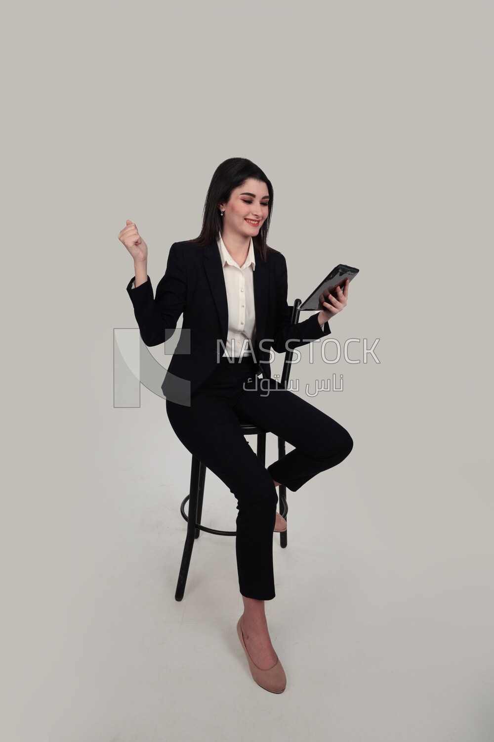 Photo of a businesswoman with a formal suit sitting on a chair and holding a tablet, business development and partnerships, business meeting, Model