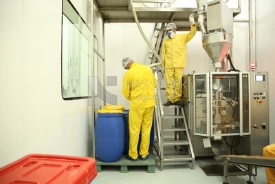 Factory workers wearing yellow suits, masks and headscarves
