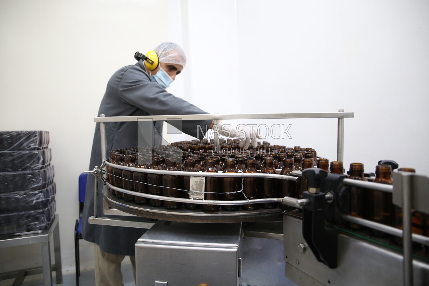 Factory worker filling bottles into a machine