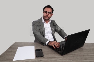 Photo of a businessman with a formal suit sitting at a desk working on a laptop, business development and partnerships, business meeting, Model