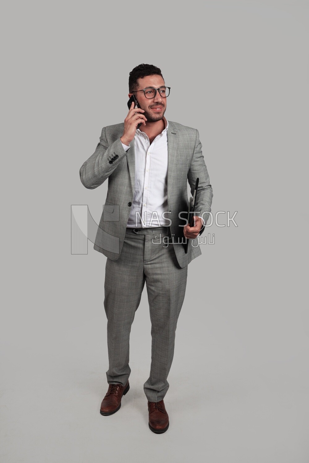 Photo of a businessman with a formal suit holding documents while talking on the phone, business development and partnerships, business meeting, Model