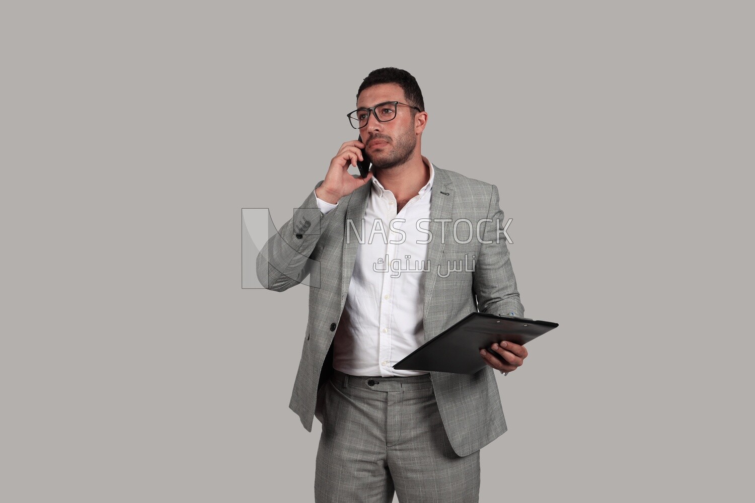 Photo of a businessman with a formal suit holding documents while talking on his phone, business development and partnerships, business meeting, Model