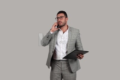 Photo of a businessman with a formal suit holding documents while talking on his phone, business development and partnerships, business meeting, Model