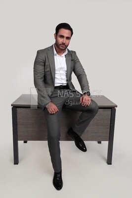 صورة لرجل أعمال يرتدي بدلة رسمية متكئًا على المكتب ، وتطوير الأعمال والشراكات ، واجتماع العمل ، موديل