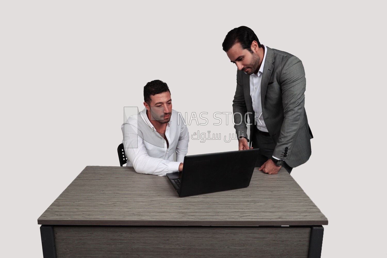 Photo of two men one sitting in the office and the other standing, discussing the work, business development and partnerships, business meeting, Model