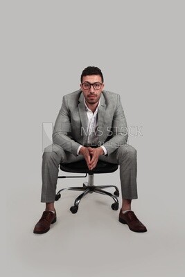 Photo of a businessman with formal wear sitting on a chair, business development and partnerships, business meeting, Model