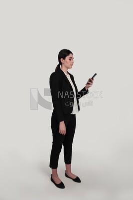 Photo of a businesswoman in formal wear standing and checking her mobile, business development and partnerships, business meeting, Model