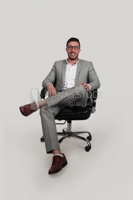 Photo of a businessman with a formal suit sitting on a chair putting a leg on a leg, business development and partnerships, business meeting, Model