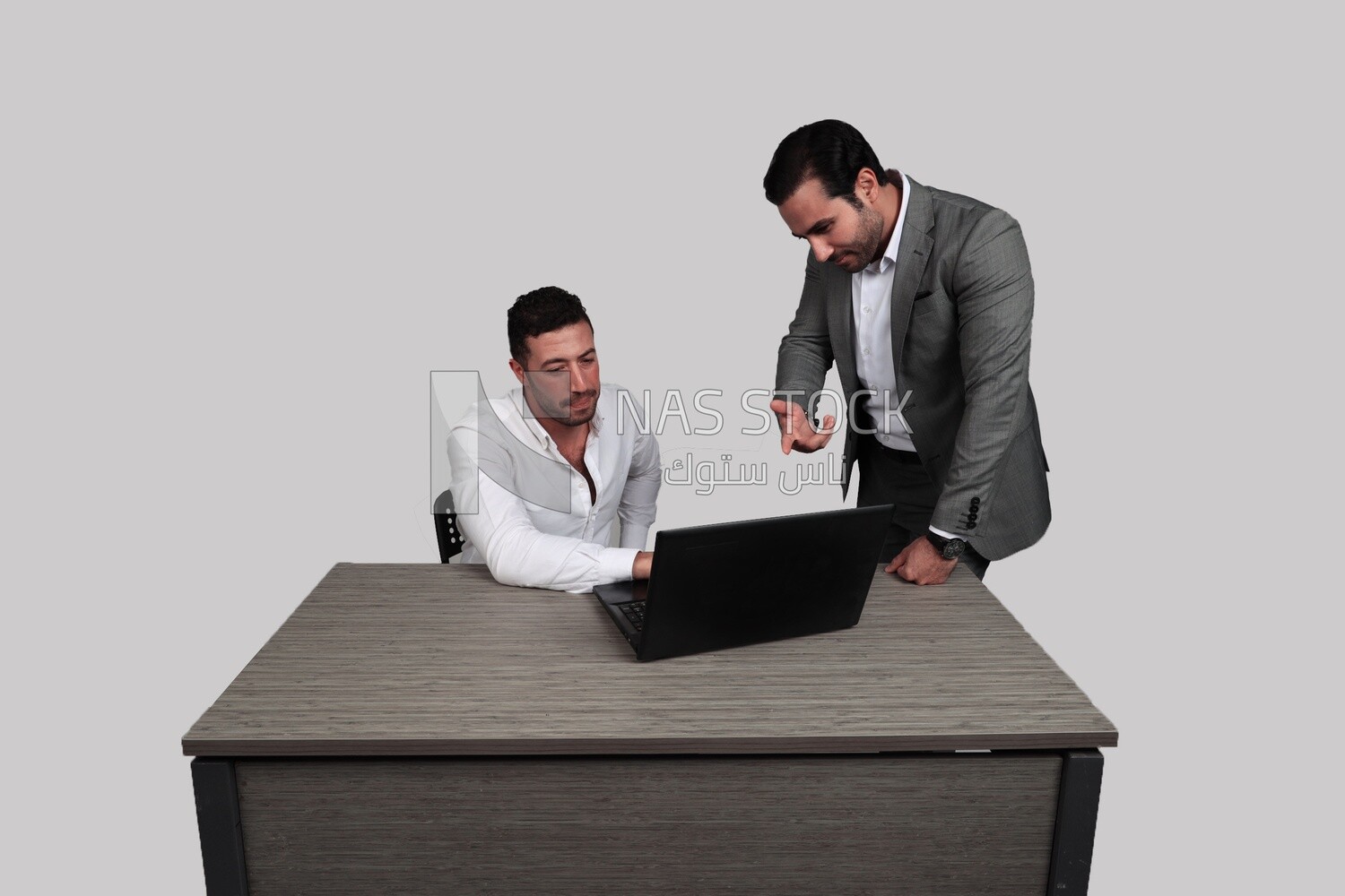 Photo of two men one sitting in the office and the other standing, discussing the work, business development and partnerships, business meeting, Model