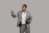 Photo of a businessman with a formal suit holding documents and pointing away, business development and partnerships, business meeting, Model