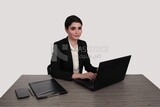 Photo of a businesswoman with a formal suit sitting at a desk working on a laptop, business development and partnerships, business meeting, Model