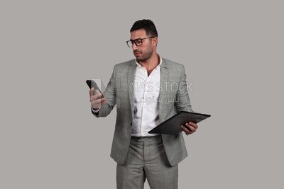 Photo of a businessman with a formal suit holding documents and checking his mobile, business development and partnerships, business meeting, Model