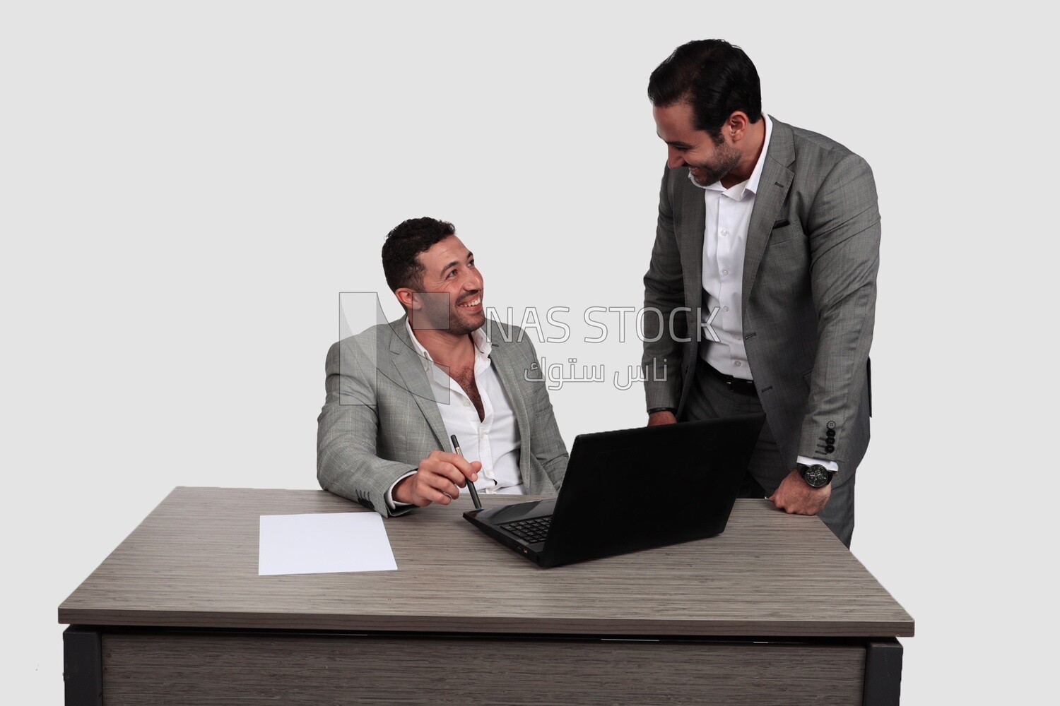 Photo of two men one sitting in the office and the other standing, discussing the work, business development and partnerships, business meeting, Model