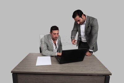 Photo of two men one sitting in the office and the other standing, discussing the work, business development and partnerships, business meeting, Model
