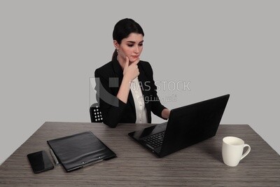 Photo of a businesswoman with a formal suit sitting at a desk working on a laptop, business development and partnerships, business meeting, Model