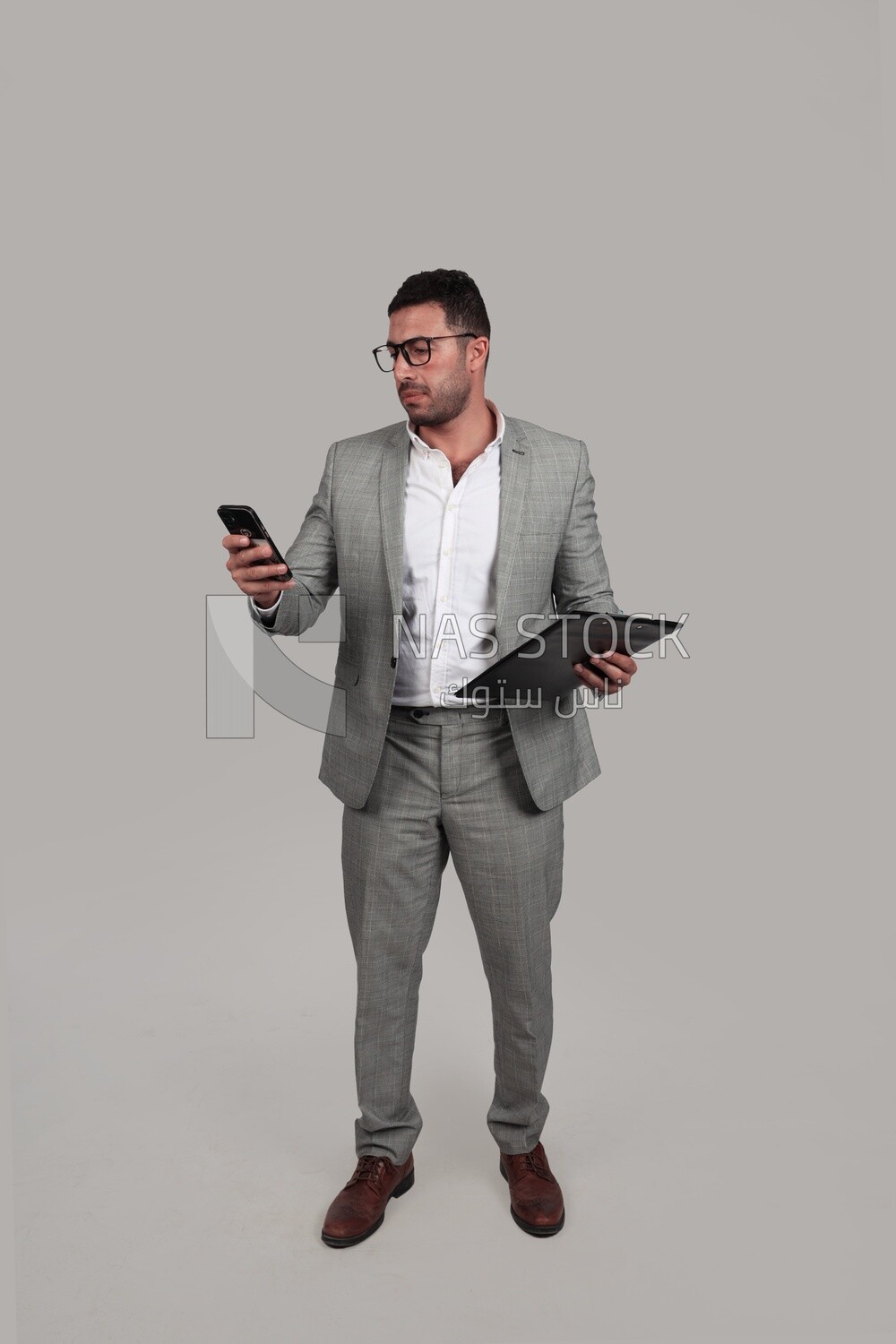 Photo of a businessman with a formal suit holding documents and checking his mobile, business development and partnerships, business meeting, Model
