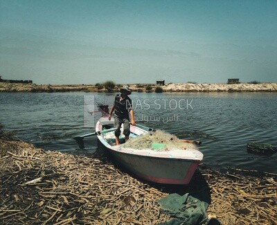 Man standing in a boat on the river, fishing, rural life, farm trees, and green plants, farm fields, trees and crops, farmland, a scenic landscape