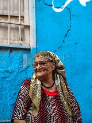 Old woman sitting on the street in front of her house, Egypt