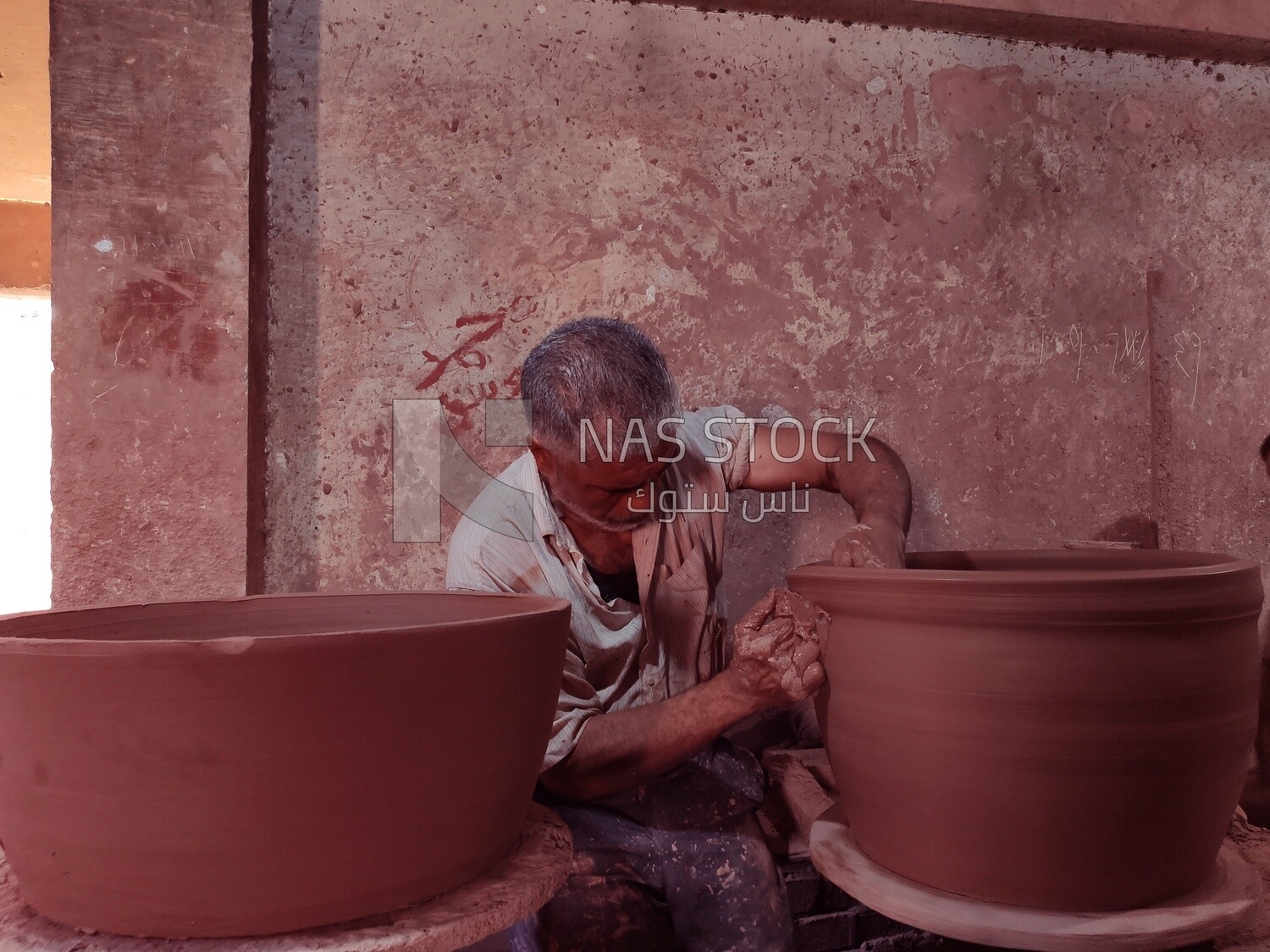 Craftsman forms a pottery vessel in a workshop