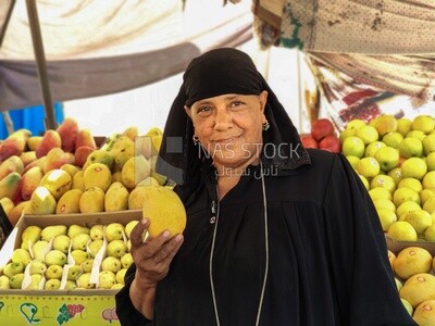 Egyptian woman holding mangoes and selling the fruit in the market