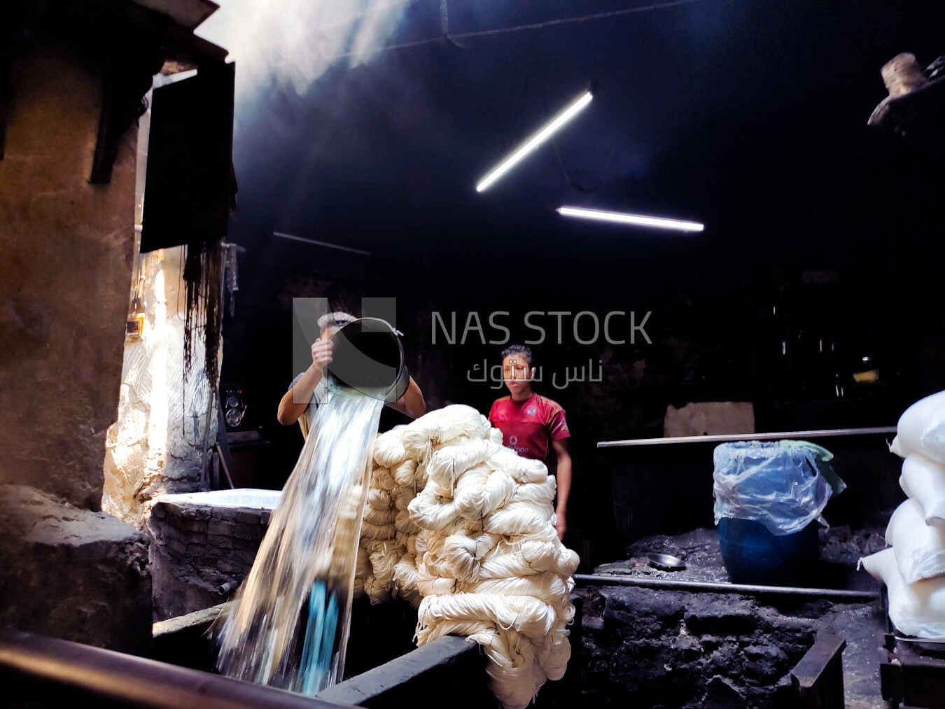 Man in a dyeing workshop fills a dyeing tub with water