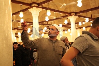رجل في المسجد ، ممسكا بهاتفه ، يصلي على السجادة ، ويؤدي صلاة الفريضة في المسجد ، ويصلي ويقترب من الله