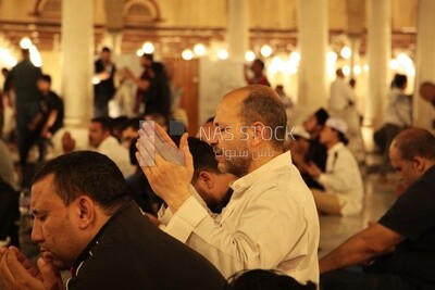 Man sitting in the mosque, praying to God, praying on the prayer rug, performing the obligatory prayer in the mosque, worship and draw close to God