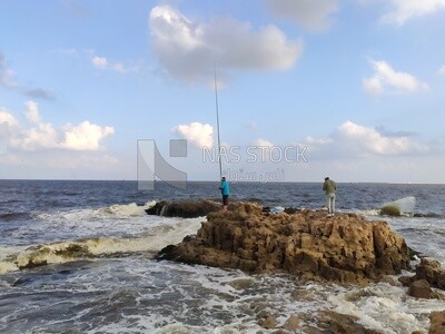 Two men standing on a rock in the middle of the sea